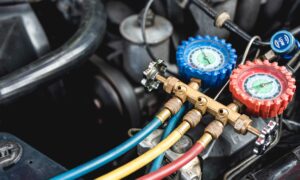 Recharging the Car air conditioner with refrigerant using professional-grade gear with separate gauges to monitor the pressure in the system.